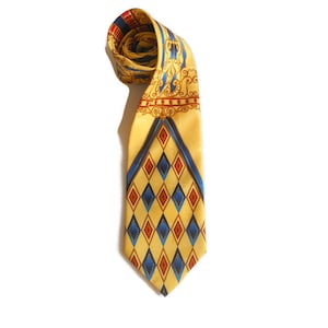 May include: A rolled-up yellow tie with a repeating pattern of blue and red diamonds. The tie has a decorative border with gold scrollwork and red accents. The tie is made of a shiny material.