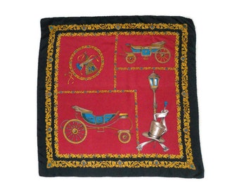 May include: A square scarf with a red center featuring illustrations of carriages, a lamppost, and a top hat. The scarf has a black border with gold and blue decorative elements.
