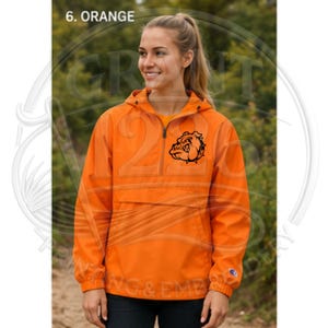 May include: An orange quarter-zip pullover jacket with a hood and a drawstring. The front features a black graphic of a bulldog head on the left chest. The sleeve cuff displays a small embroidered logo. The text 6. ORANGE appears at the top.