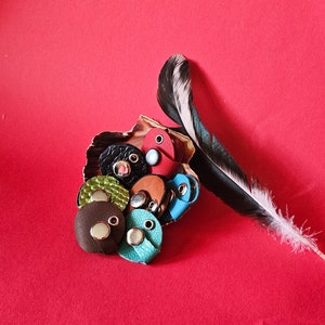 Könnte beinhalten: Eine Sammlung bunter Lederkordelenden mit Metallringen. Die Kordelenden sind in einem Kreis auf rotem Hintergrund angeordnet.