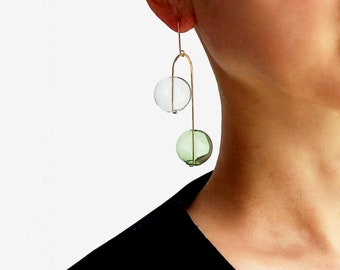 May include: Gold dangle earrings with two glass spheres, one clear and one green.