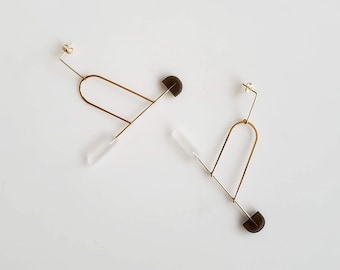 May include: A pair of gold geometric earrings with clear and dark grey semi-circle accents.