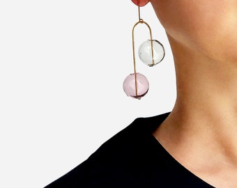 May include: Gold dangle earrings with two glass spheres, one clear and one pink.