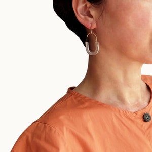 May include: A pair of clear acrylic earrings with a gold hoop and a U-shaped design.