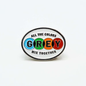 May include: A white enamel pin with a silver border. The pin says "All the colors mix together" and has the word "GREY" in colorful circles.