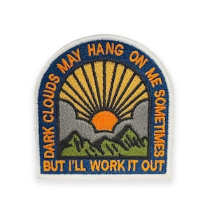 May include: Embroidered patch with a navy blue border and the text "DARK CLOUDS MAY HANG ON ME SOMETIMES BUT I'LL WORK IT OUT". The patch features a mountain scene with a yellow sunburst and an orange sun.
