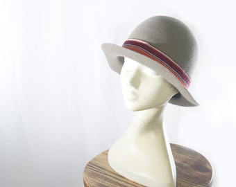 Grey colored bowler hat, with a round and high crwon and a short brim, handmade of wool felt