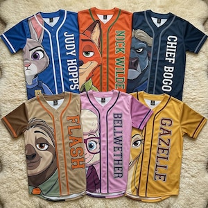 Op de afbeelding: Honkbalshirts met personages uit Zootopia. De shirts zijn in verschillende kleuren, waaronder blauw, oranje en geel, met afbeeldingen van personages en namen als "Judy Hopps" en "Nick Wilde". De shirts hebben knoopsluitingen en korte mouwen.