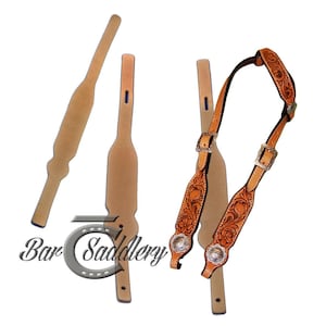 Puede incluir: Una cabezada de cuero color canela con intrincados grabados florales, hebillas plateadas y conchos decorativos. El conjunto incluye correas de cuero liso adicionales y un logotipo que dice Bar Saddlery. El cuero es marrón claro con bordes oscuros.