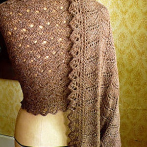 Puede incluir: Una chal de punto marrón con un patrón de encaje y un borde con flecos.