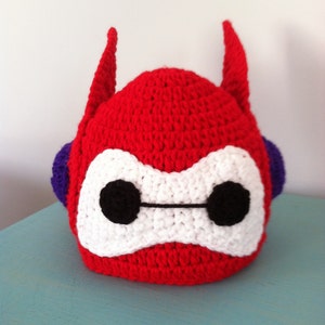May include: Red, white, and purple crocheted hat shaped like the character Baymax from the Disney movie Big Hero 6.
