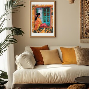Peut inclure: Une impression encadr&eacute;e d'une femme en sari color&eacute; assise pr&egrave;s d'une fen&ecirc;tre avec une porte turquoise. La fen&ecirc;tre est entour&eacute;e de fleurs et de feuilles jaunes. L'impression est accroch&eacute;e &agrave; un mur beige au-dessus d'un canap&eacute; blanc avec des coussins.
