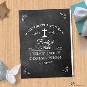 May include: A black and white chalkboard style card with the text "Congratulations Bridget on your First Holy Communion". The card has a white cross and decorative flourishes.