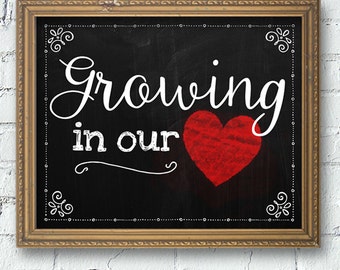 May include: A black chalkboard with a gold frame, featuring the text "Growing in our" in white cursive lettering, with a large red heart in the center.