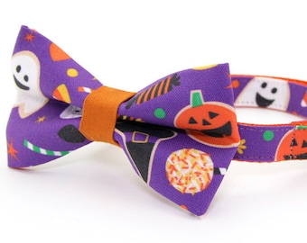 May include: Purple cat collar with a matching bow tie featuring a Halloween print of ghosts, pumpkins, candy corn, and witch hats. The collar has a bell.