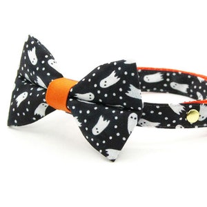 Peut inclure: Collier pour chat noir et blanc avec un n&oelig;ud papillon &agrave; motif fant&ocirc;me. Le collier est dot&eacute; d'une bordure orange et d'une clochette.