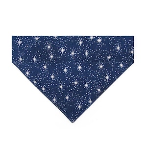 May include: A triangular pet bandana in a deep navy blue color featuring a repeating pattern of white stars and small dots. The fabric has a distinct celestial design with various sizes of four-pointed stars scattered across the entire surface.