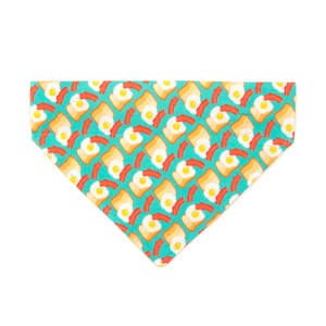 May include: A turquoise blue dog bandana with a repeating pattern of yellow eggs, orange bacon, and brown toast.