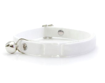 May include: White cat collar with a silver bell and a buckle closure.