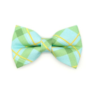 May include: A plaid bow tie in shades of light blue, green, and yellow. The bow tie features a classic plaid pattern with intersecting lines. The bow tie is a stylish accessory for formal or casual wear.