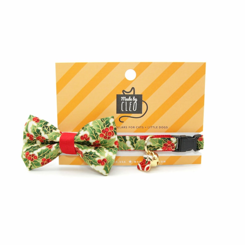 May include: A green and red Christmas-themed cat collar with a matching bow tie. The collar has a bell and a small stocking charm. The collar is made by Cleo and is for cats and small dogs.