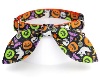 May include: A black pet collar featuring a vibrant Halloween-themed pattern of orange pumpkins, white ghosts, green skulls, purple witch hats, and candy corn. The collar includes an attached fabric bow tie and a silver metal D-ring for attachment.