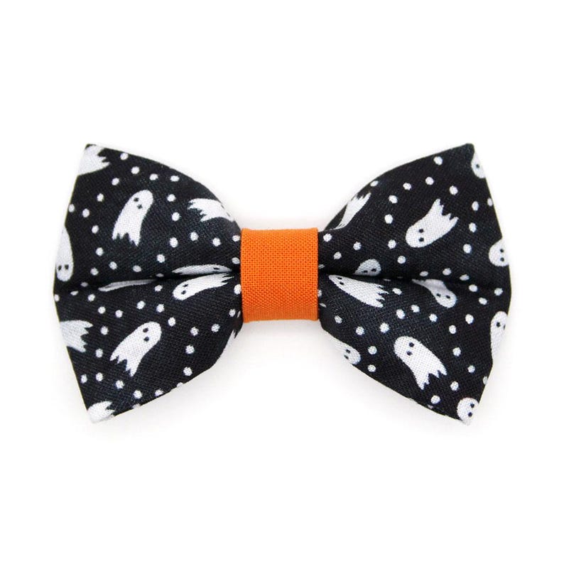 Peut inclure: Noeud papillon noir avec un motif de fant&ocirc;mes blancs et de pois. Le noeud papillon a un centre orange.