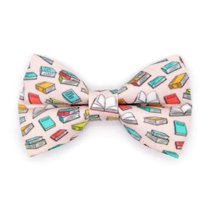 May include: A pink bow tie with a pattern of colorful books and open books.