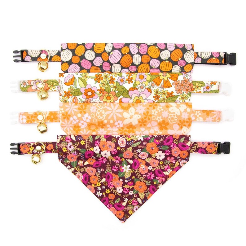 May include: Set of four colourful cat collars with bell charms. The collars feature different floral and pumpkin patterns.