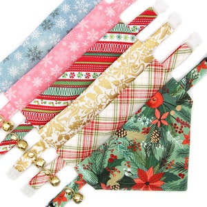 May include: Five different Christmas-themed dog bandanas with bells. The bandanas are in a variety of colors and patterns, including red, green, white, gold, and blue. The bandanas are arranged in a fan shape, with the green bandana at the bottom.