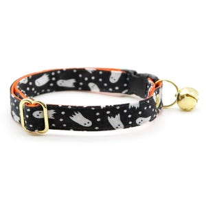 Peut inclure: Collier pour chat noir et orange avec un motif de fant&ocirc;mes blancs et une clochette dor&eacute;e.