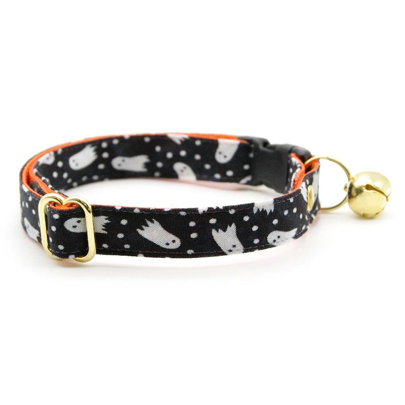 Peut inclure: Collier pour chat noir et orange avec un motif de fant&ocirc;mes blancs et une clochette dor&eacute;e.