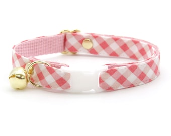 May include: Pink and white gingham cat collar with a gold bell and a white plastic buckle.