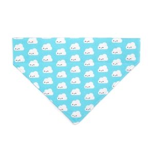 May include: A light blue triangular pet bandana with a repeating pattern of white smiling cloud illustrations. The bandana is made of a soft fabric and is designed to be worn around a pet's neck.