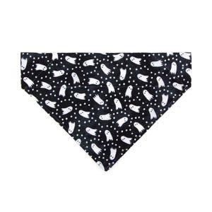 May include: Black and white dog bandana with a ghost pattern. The bandana is triangular in shape and has white ghosts on a black background.