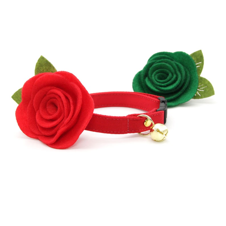 May include: A red felt rose with green leaves attached to a red velvet cat collar with a gold bell.