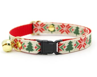 May include: A festive cat collar with a Christmas tree and snowflake pattern in red, green, and white. The collar has a gold bell and a black plastic buckle. The inner lining is red.