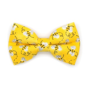 May include: A yellow bow tie with a pattern of black bees and silver glitter.