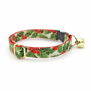 May include: A green, red, and gold cat collar with a holly berry pattern and a small bell.