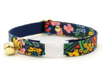 May include: A blue and floral patterned cat collar with a white buckle and a gold bell.