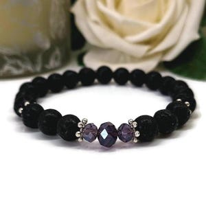 May include: Black lava stone bracelet with faceted purple crystal beads and silver accents. The bracelet has a stretch design. The beads are approximately 0.8 cm in diameter. Suitable for everyday wear.