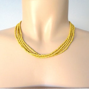 May include: A multi-strand necklace made of small, matte gold beads. The necklace is layered and has a simple, elegant design.