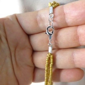 May include: A gold beaded necklace with a silver lobster clasp closure.