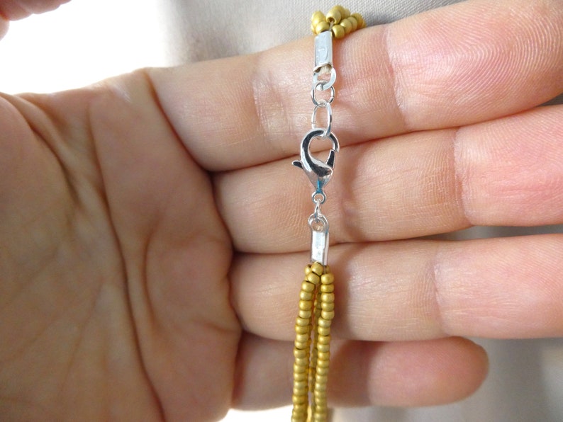 May include: A gold beaded necklace with a silver lobster clasp closure.