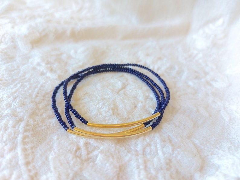 May include: A navy blue beaded bracelet with two gold metal bars.