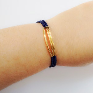May include: A navy blue beaded bracelet with three gold rings.