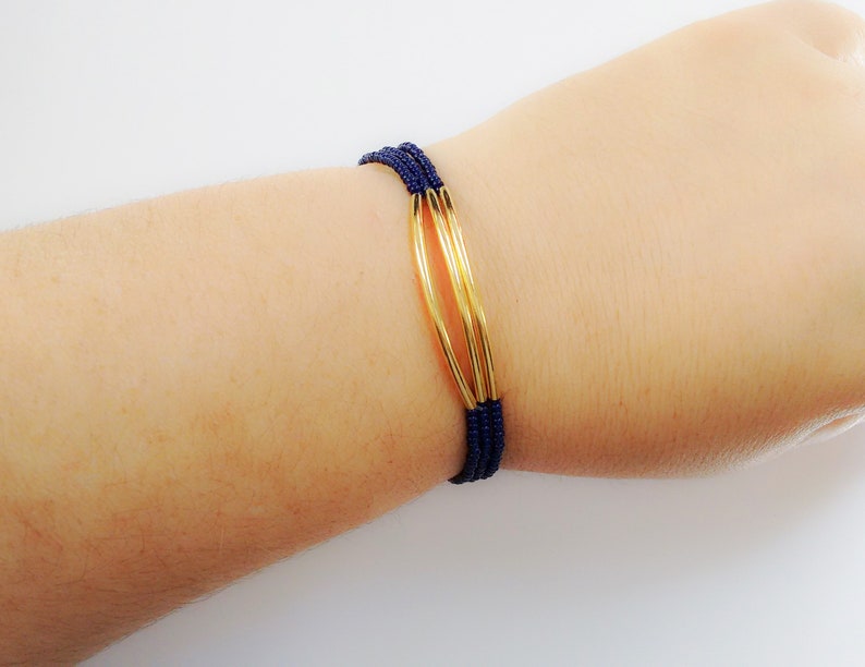 May include: A navy blue beaded bracelet with three gold rings.