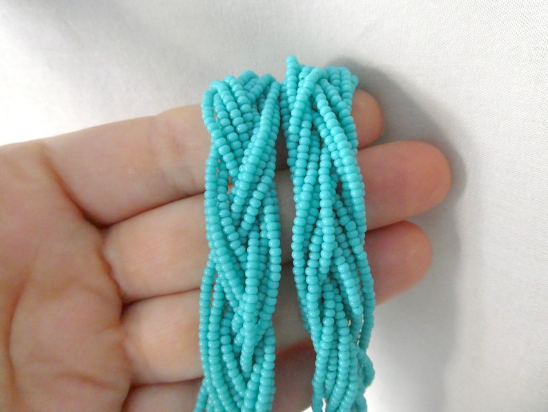 May include: A strand of turquoise blue seed beads, braided together in a rope-like shape.