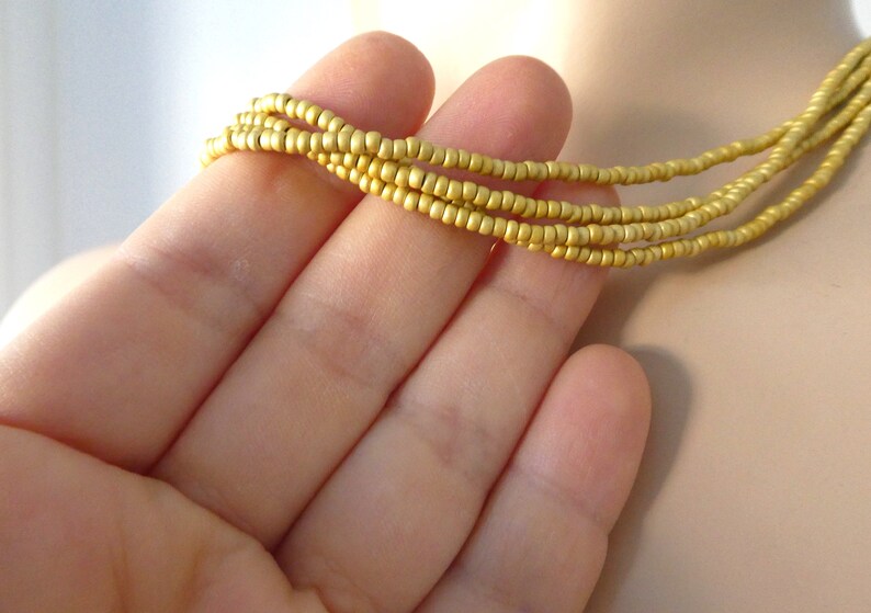 May include: A gold beaded necklace with multiple strands of small, round beads.