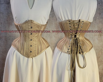 Può includere: Un corsetto beige dal design strutturato, con pannelli verticali e una sezione inferiore in rete. Il corsetto ha una chiusura frontale con piccoli bottoni e un retro allacciato. Il corsetto è esposto su un manichino con un vestito bianco.